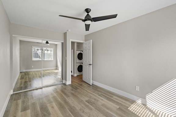 an empty living room with a ceiling fan and a door to a laundry room at Ocean Breeze Terrace Apartment, Huntington Beach