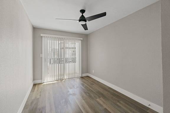 the living room of an apartment with sliding glass doors and a ceiling fan at Ocean Breeze Terrace Apartment, California