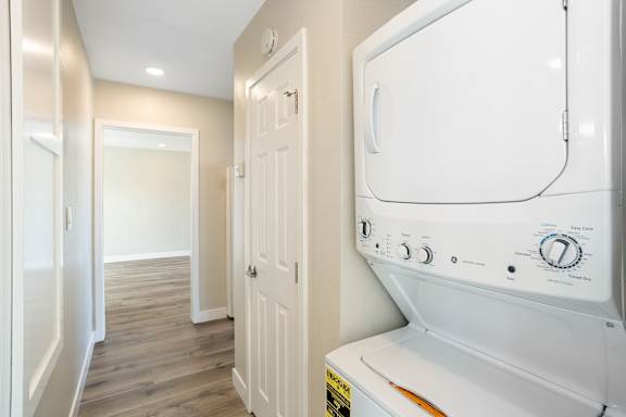 a laundry room with a washer and dryer and a hallway with a door