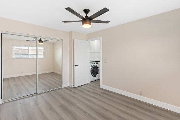 a bedroom with a large window and a ceiling fan