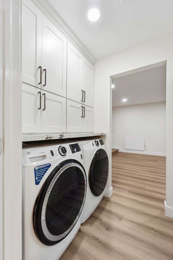 a washer and dryer in a laundry room with white cabinets