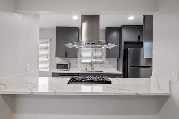 a modern kitchen with white marble counter tops and black cabinets