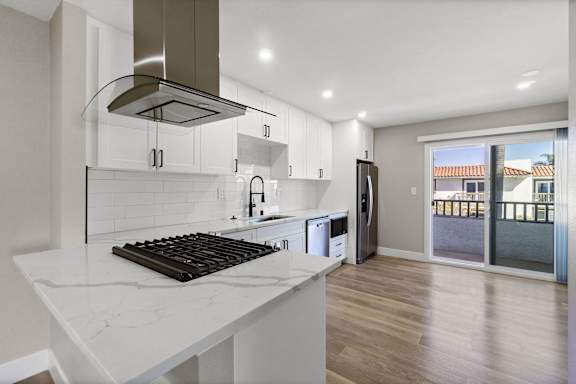 an open kitchen with white cabinets and a marble counter top at Ocean Breeze Terrace Apartment, Huntington Beach, 92648