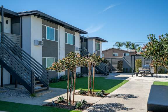 A sunny day at a modern apartment complex with a staircase and a picnic table.