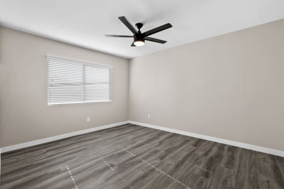 A room at 316 Beach Apartments with a ceiling fan and a window with blinds.