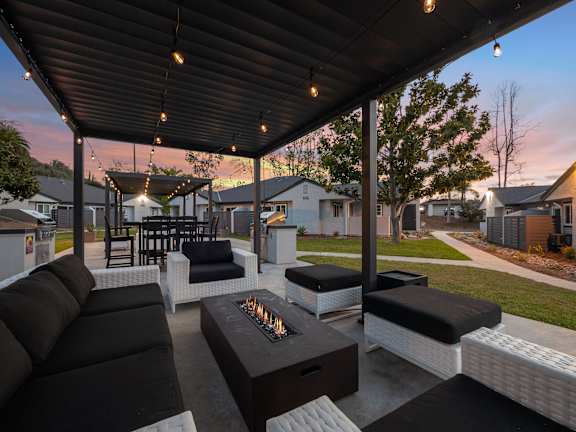 A patio with a black and white couch, a coffee table, and string lights.