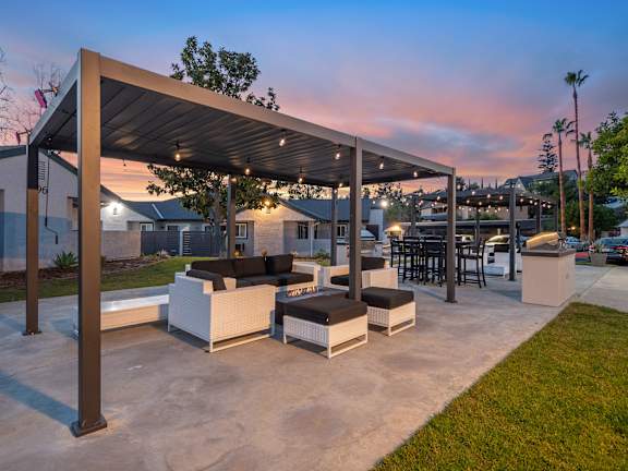 A patio area with a white couch and a black cushion is under a roof.