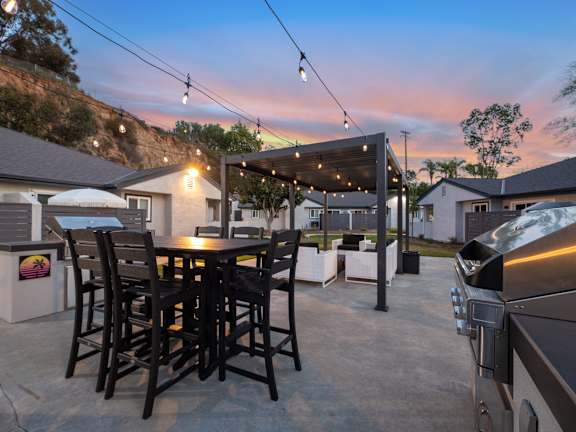 A patio with a table and chairs under string lights.