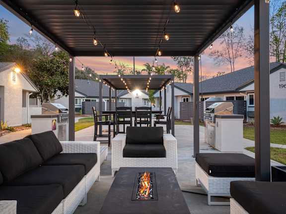 A patio with a black couch and a fire pit.