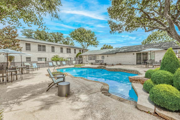 Outdoor pool area with lounge chairs at Northwood Heights Apartments, Dallas, Texas