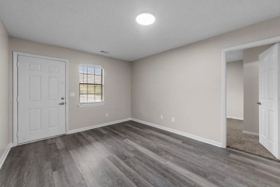 an empty living room with wood flooring and a white door