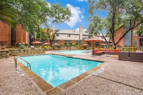 A pool surrounded by trees and a building in the background.