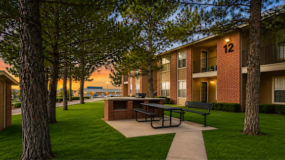 Community courtyard with picnic table and brick grill at Las Lomas Apartments, Texas