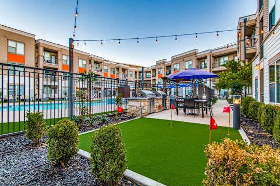 A pool area with a table and chairs and a blue umbrella.