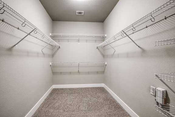 A sparsely furnished walk-in closet with metal racks and a carpeted floor.