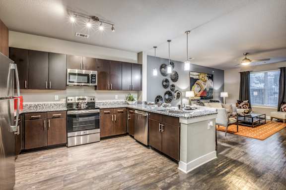 A modern kitchen with dark wood floors and stainless steel appliances.
