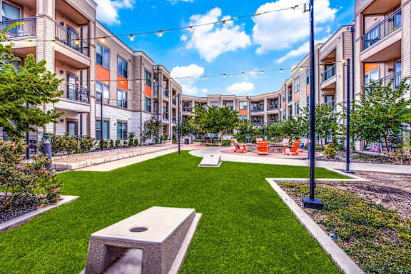 A sunny day at a residential complex with a well-maintained lawn and benches.