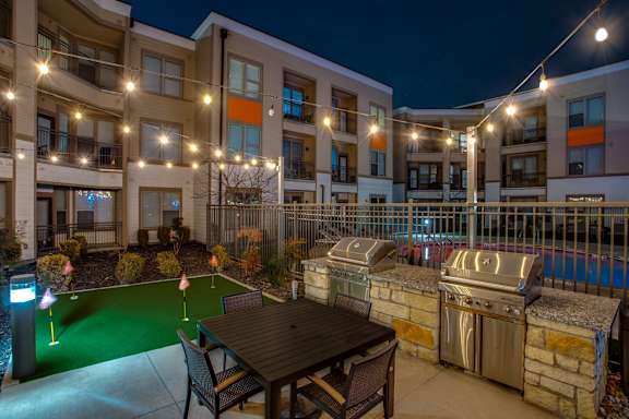 A patio with a table and chairs is surrounded by apartment buildings.