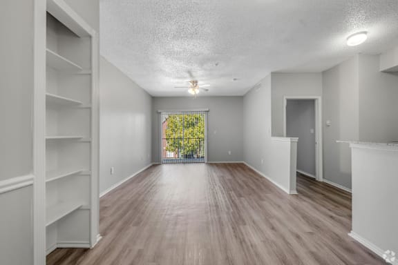 A spacious room with wooden flooring and white walls.