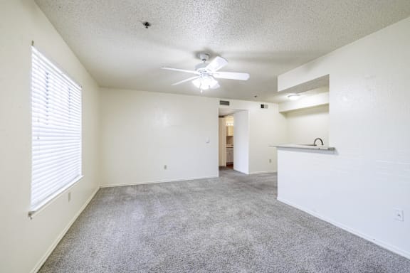 A spacious room with a ceiling fan and carpeted floor.