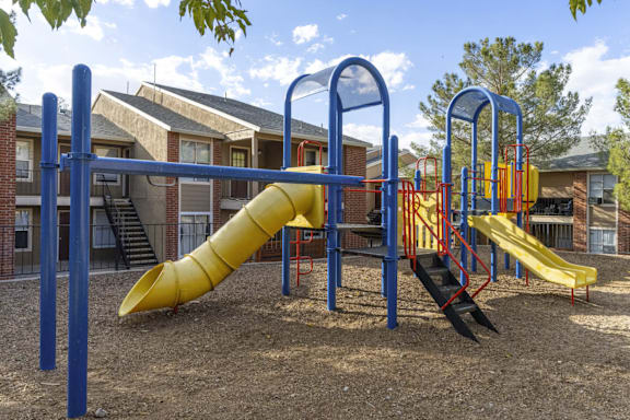 Colorful playground with tube slide and climbing features at Las Lomas Apartments, El Paso, TX 79912
