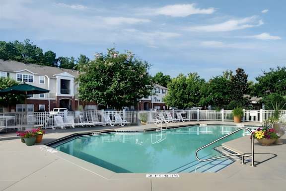 A pool with a slide and chairs around it.