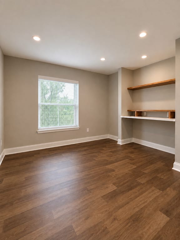 A room with wooden floors and a window with blinds.