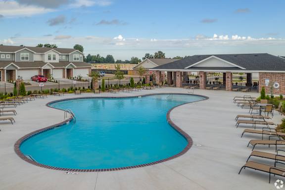 A large outdoor swimming pool surrounded by lounge chairs at Cedar Crest Apartments, Farmington, Arkansas