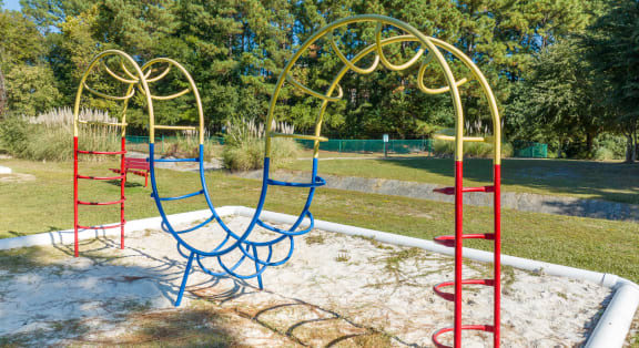 a swing set in a park with trees in the background