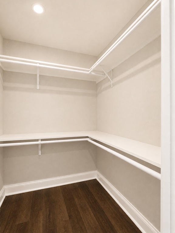 Empty walk-in closet with white shelves and wooden floors.