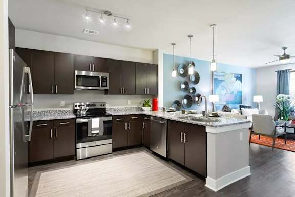 A modern kitchen with dark brown cabinets and stainless steel appliances.