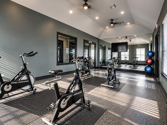 A gym with exercise bikes and a mirror.