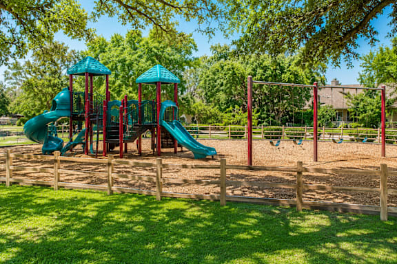 A playground with a green slide and red and blue towers.