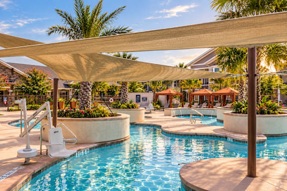 A pool area with a sun shade and a slide.