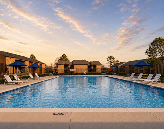 Large swimming pool with lounge chairs and umbrellas at Ridgeview Apartments, Texas, 75092