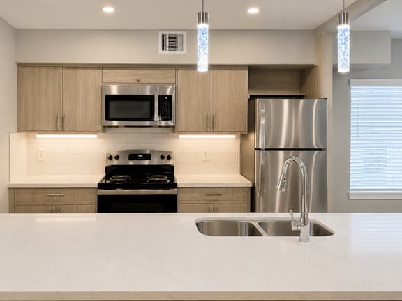 A modern kitchen with a stainless steel refrigerator and a white countertop.