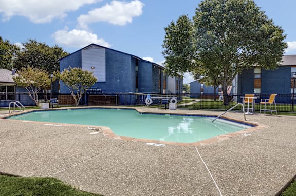 A swimming pool in front of a building with a tree.
