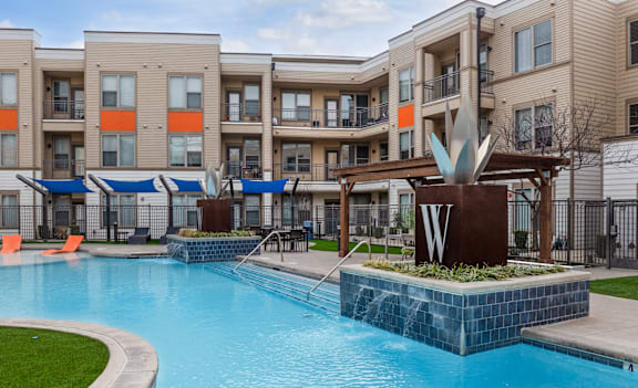 A large pool in front of a building with a sculpture in the middle of the pool.