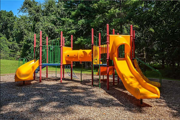 A playground with a yellow slide and a green and red structure.
