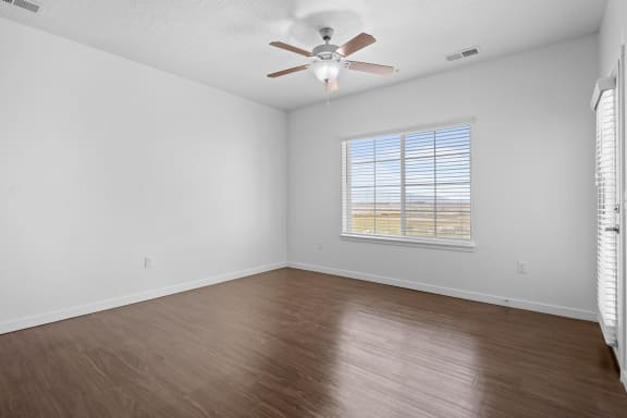 an empty living room with wood floors and a ceiling fan