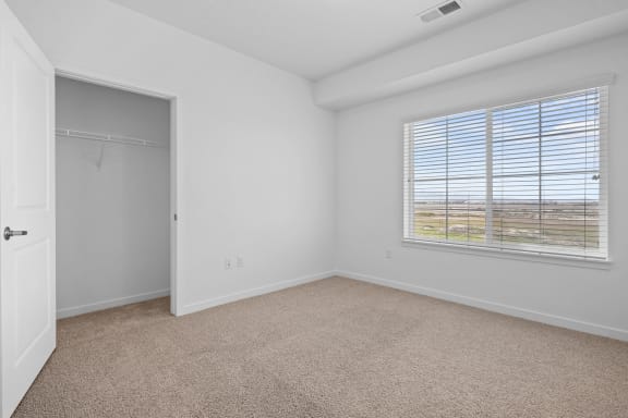 an empty bedroom with a closet and a large window