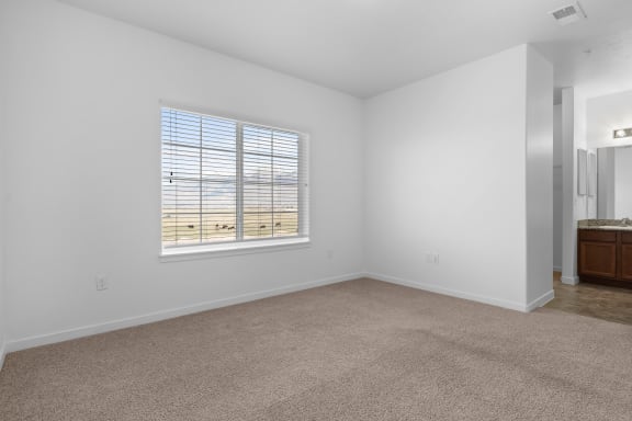 an empty bedroom with a window and a bathroom