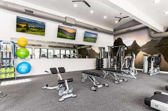 A gym with a variety of equipment including weights and exercise balls.