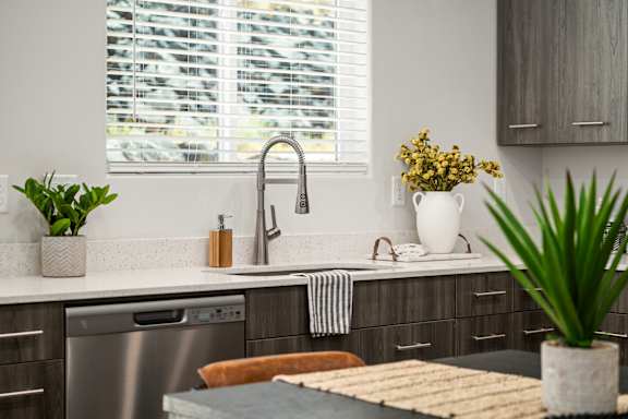 A modern kitchen with a stainless steel dishwasher and a sink with a faucet.
