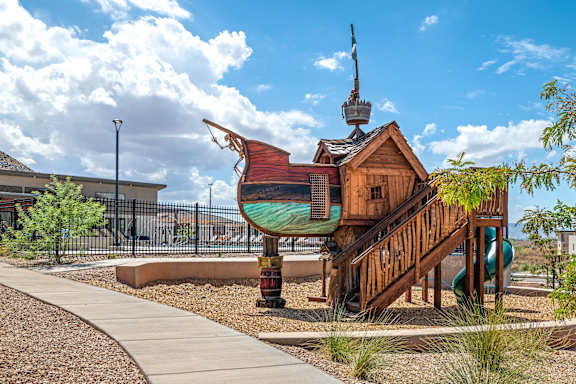 A playground with a wooden pirate ship structure and a green slide.