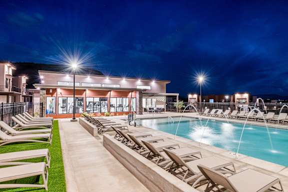 A poolside area with lounge chairs and a building in the background.