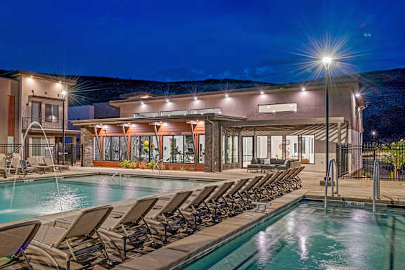 A poolside area with lounge chairs and a building in the background.