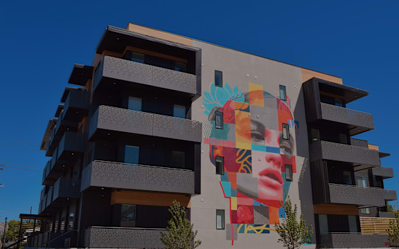 A large mural of a woman's face is painted on the side of a building.