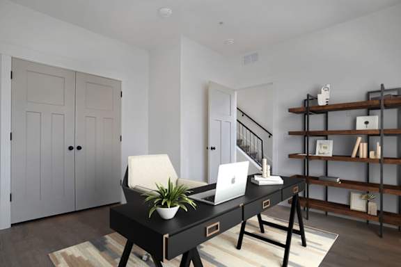 A black desk with a laptop and a plant on it.