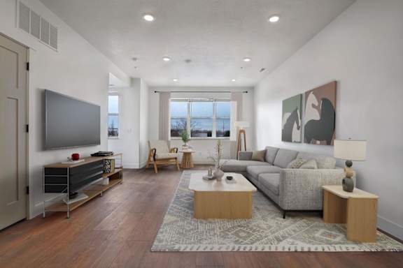 A modern living room with a grey sofa, wooden coffee table, and a television.
